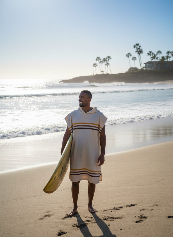 Man holding a surfboard on a beach with palm trees and ocean waves in the background